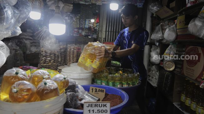 Pedagang menata minyak goreng di tokonya di Pasar Minggu, Jakarta, Rabu (26/1/2022). (Foto: Suara.com/Angga)