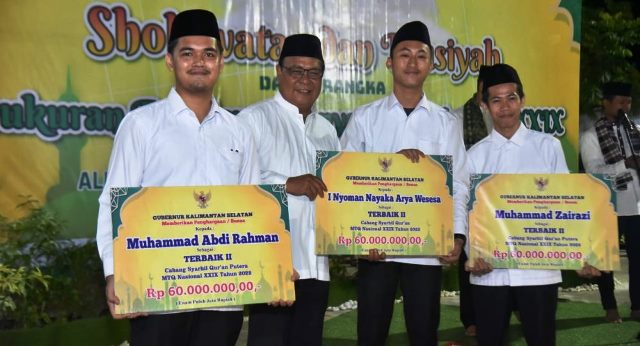 Gubernur Kalsel H Sahbirin Noor atau Paman Birin (dua kiri) secara simbolis menyerahkan bonus bagi anggota kafilah asal Kalsel yang mendapat juara di MTQN, Rabu (9/11/2022) malam di Desa Kiram Karang Intan Kabupaten Banjar. (Foto: Adpim Setdaprov Kalsel)